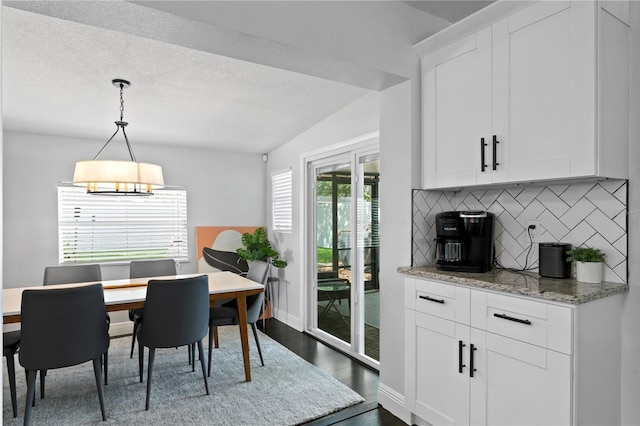 dining area with dark wood-type flooring, a chandelier, and baseboards