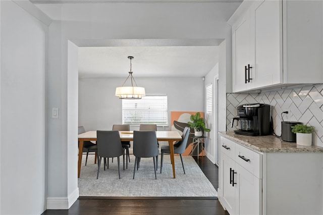dining room with dark wood-type flooring, baseboards, and a chandelier