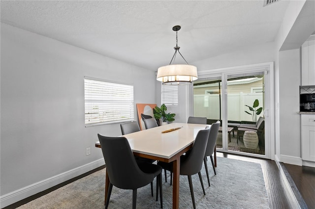 dining space with baseboards, dark wood-type flooring, and a chandelier