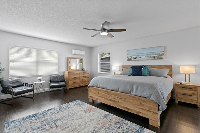 bedroom with a wall mounted air conditioner, wood finished floors, a textured ceiling, and ceiling fan