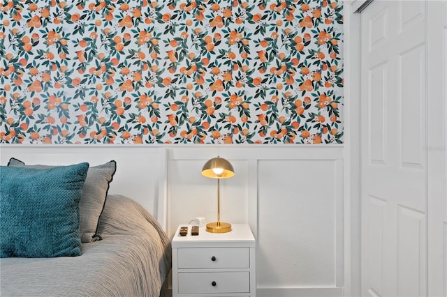 bedroom featuring a wainscoted wall and a decorative wall