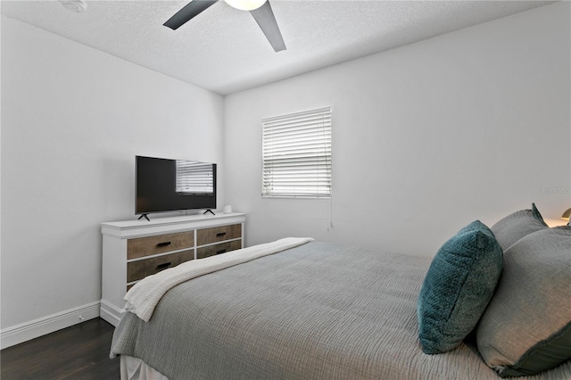 bedroom featuring dark wood-style flooring, a ceiling fan, and baseboards