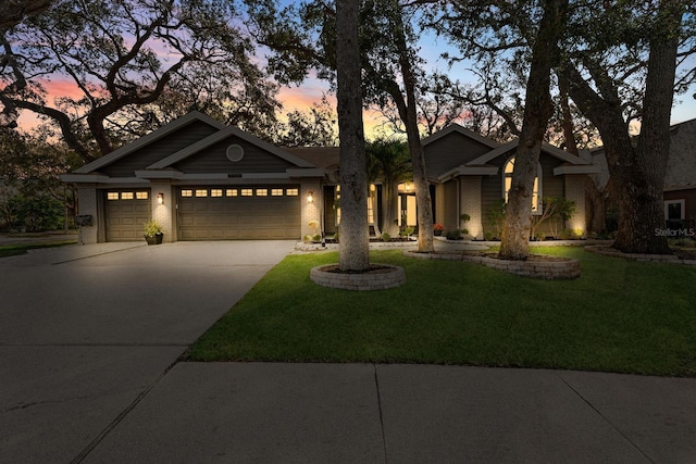 view of front facade with a garage, concrete driveway, brick siding, and a lawn