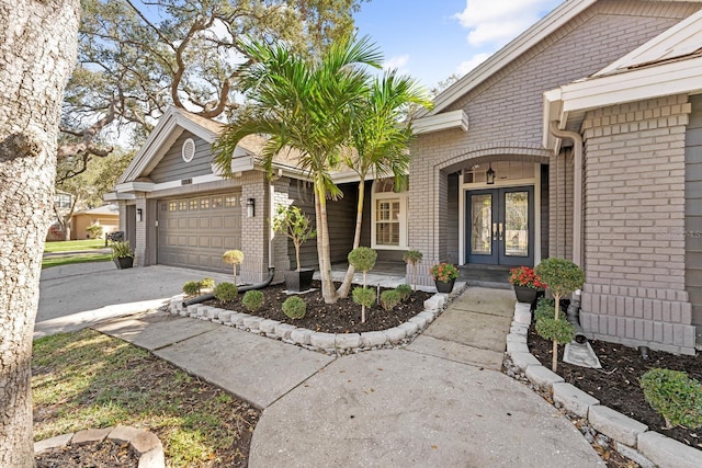 entrance to property with driveway, brick siding, a garage, and french doors