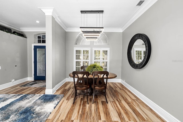 dining area with baseboards, wood finished floors, visible vents, and crown molding