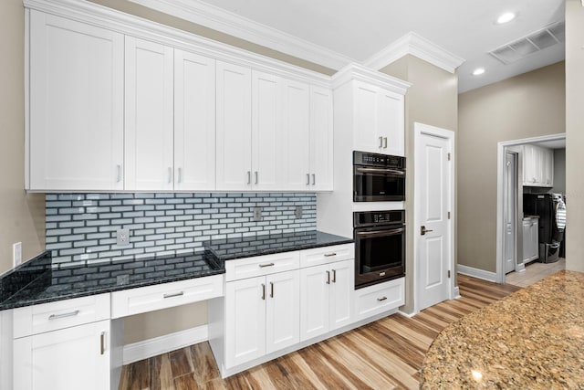 kitchen with tasteful backsplash, visible vents, white cabinets, dark stone counters, and double oven