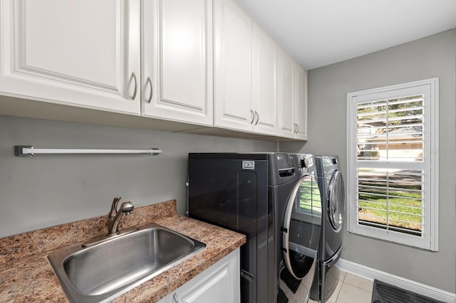 clothes washing area featuring light tile patterned floors, a sink, baseboards, washer and dryer, and cabinet space