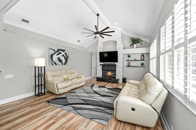 living area with wood finished floors, baseboards, vaulted ceiling, ornamental molding, and a brick fireplace