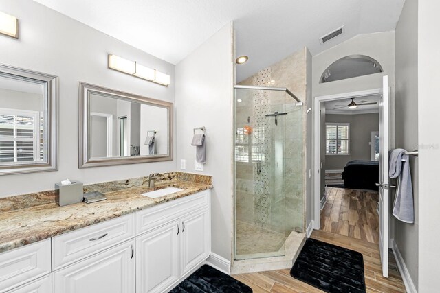 ensuite bathroom featuring visible vents, a stall shower, connected bathroom, vaulted ceiling, and wood finished floors