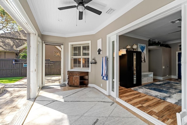 doorway to outside featuring ornamental molding, wood finished floors, visible vents, and baseboards