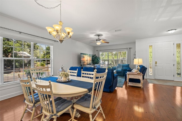 dining area featuring visible vents, ceiling fan with notable chandelier, hardwood / wood-style flooring, and baseboards