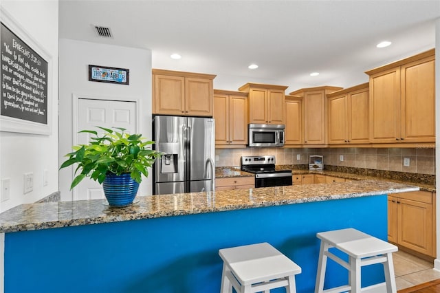 kitchen featuring recessed lighting, tasteful backsplash, stainless steel appliances, and a kitchen breakfast bar