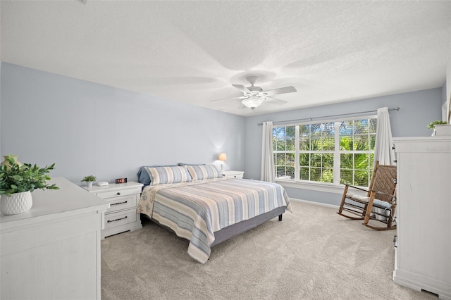 bedroom featuring light carpet, baseboards, a ceiling fan, and a textured ceiling