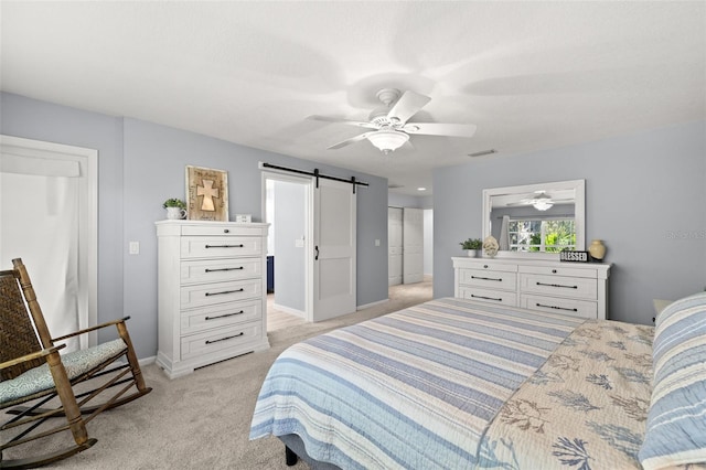 bedroom featuring a barn door, light carpet, visible vents, a ceiling fan, and baseboards