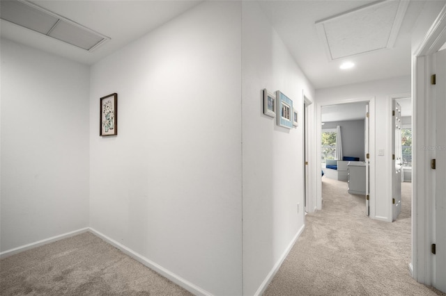 hallway with carpet flooring, attic access, and baseboards