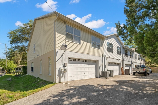 view of front of property with an attached garage, cooling unit, and stucco siding