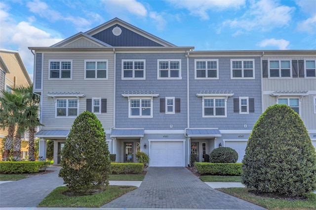 multi unit property featuring a garage and decorative driveway