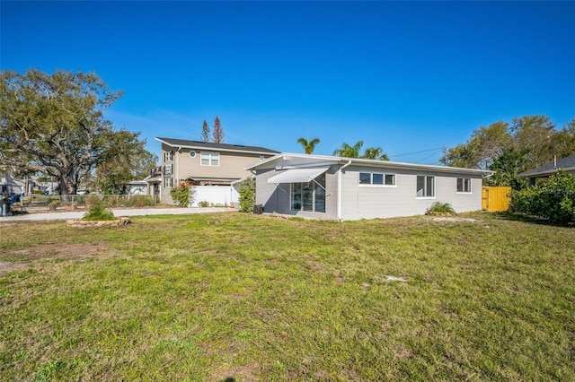 back of house with a lawn and fence