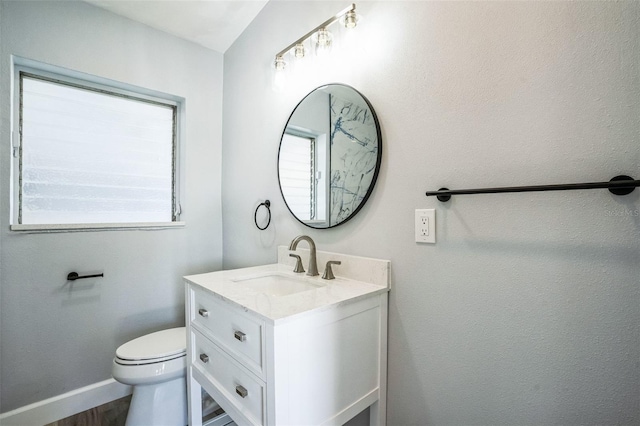 half bathroom featuring baseboards, vanity, toilet, and wood finished floors