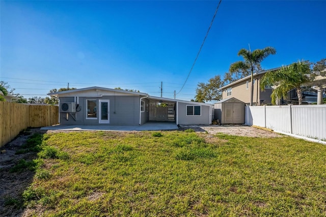 back of house featuring a fenced backyard, a storage unit, a yard, a patio area, and an outdoor structure