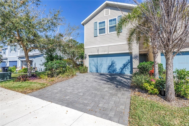 view of front of home featuring a garage, decorative driveway, and stucco siding