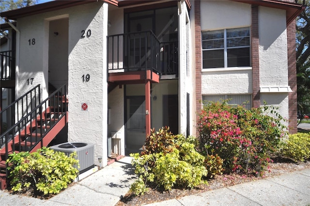 entrance to property featuring cooling unit and stucco siding