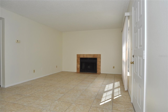 unfurnished living room with light tile patterned floors, baseboards, a textured ceiling, and a tile fireplace