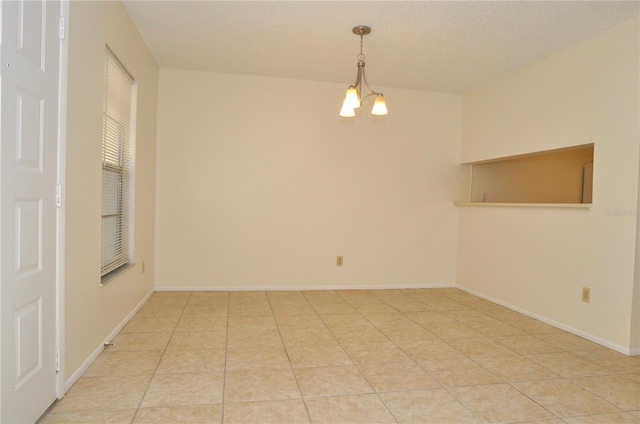 unfurnished room featuring light tile patterned flooring, a textured ceiling, baseboards, and an inviting chandelier