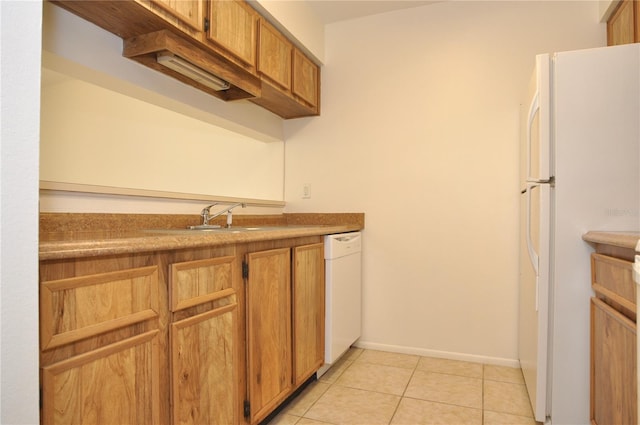 kitchen with brown cabinets, light tile patterned flooring, a sink, white appliances, and baseboards