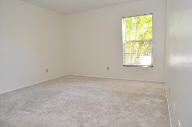 spare room featuring light carpet and baseboards