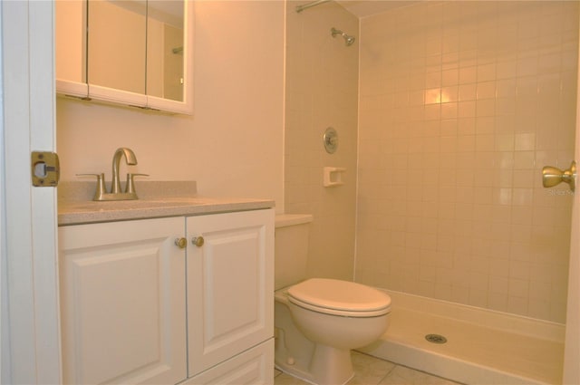 full bath featuring toilet, tile patterned floors, a tile shower, and vanity