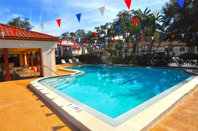 community pool with a patio and fence