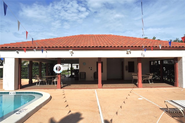 back of property featuring outdoor dining area, a patio area, and a community pool