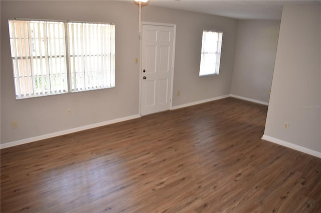 spare room featuring baseboards and wood finished floors