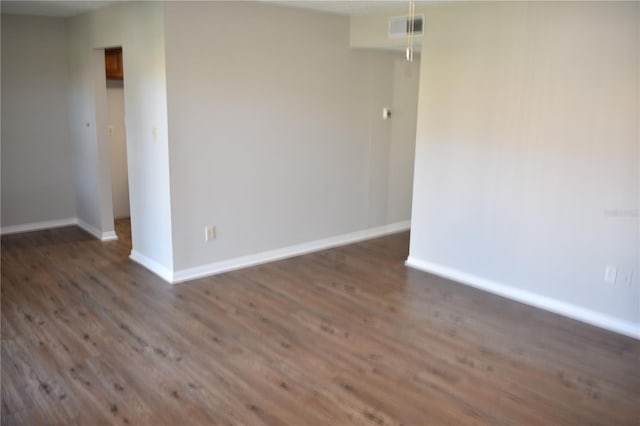 empty room with wood finished floors, visible vents, and baseboards