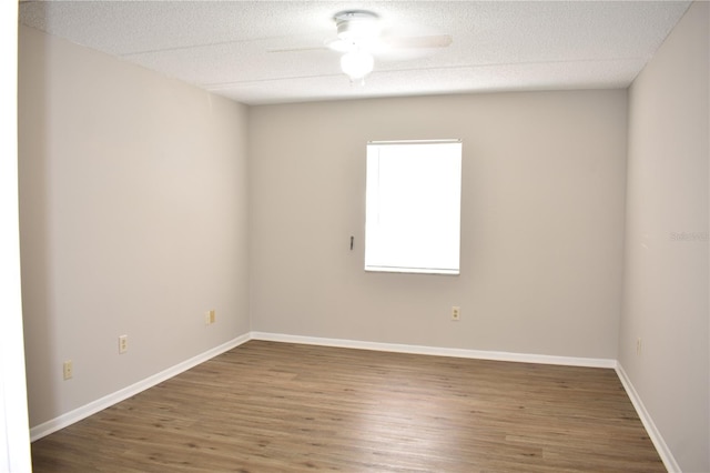 spare room featuring a ceiling fan, a textured ceiling, baseboards, and wood finished floors