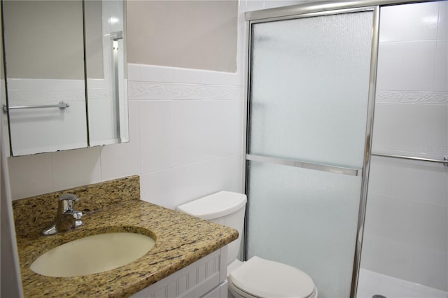 full bathroom featuring toilet, a stall shower, tile walls, and vanity