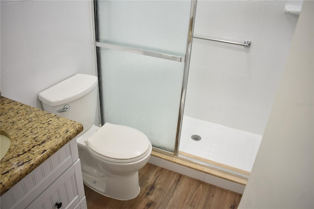 bathroom with toilet, a shower stall, wood finished floors, and vanity