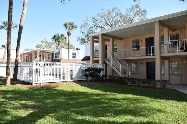 exterior space featuring stairway, a front yard, fence, and stucco siding