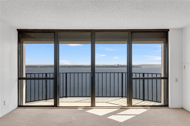 unfurnished room featuring floor to ceiling windows, a textured ceiling, a water view, and carpet floors