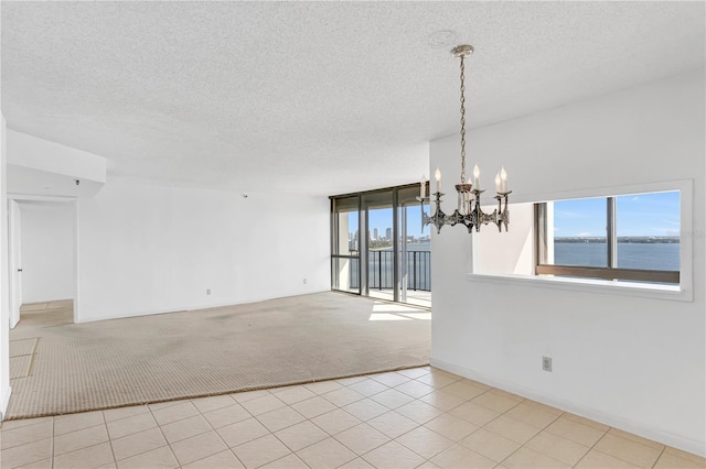 empty room featuring an inviting chandelier, carpet flooring, a wealth of natural light, and a textured ceiling