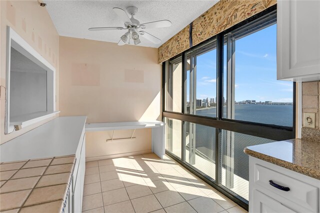 bathroom featuring a view of city, a textured ceiling, ceiling fan, and tile patterned flooring