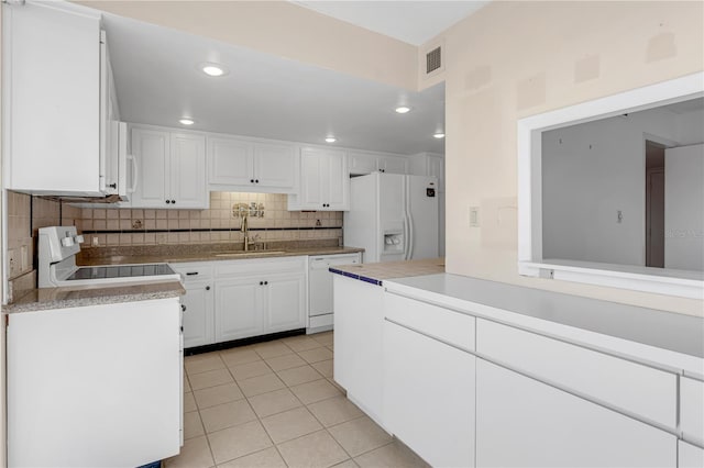 kitchen with visible vents, backsplash, light tile patterned floors, white appliances, and a sink