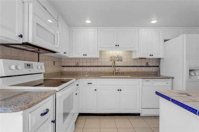 kitchen featuring a sink, white appliances, white cabinets, light tile patterned floors, and decorative backsplash