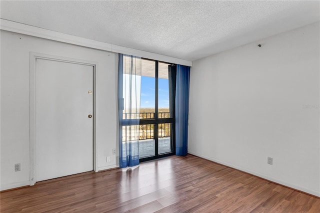 spare room featuring floor to ceiling windows, wood finished floors, and a textured ceiling