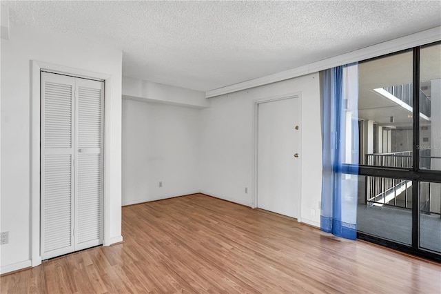 unfurnished room with plenty of natural light, floor to ceiling windows, a textured ceiling, and wood finished floors