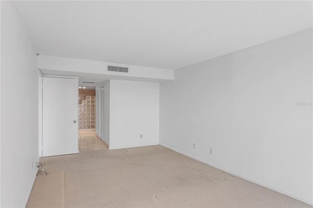 unfurnished room featuring light carpet, visible vents, and a textured ceiling