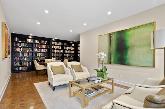 sitting room with bookshelves, recessed lighting, and baseboards