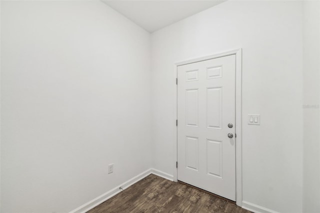 empty room with dark wood-style flooring and baseboards