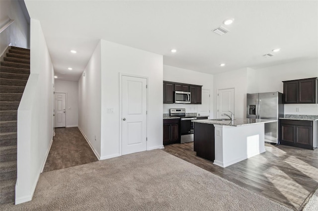 kitchen with dark brown cabinetry, recessed lighting, visible vents, appliances with stainless steel finishes, and an island with sink